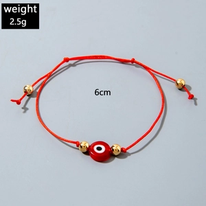 Macro view of red evil eye charm bracelet with gold beads and adjustable cord strap