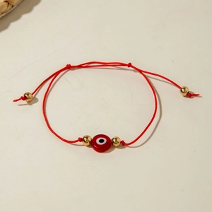 Detail of red Evil Eye beaded bracelet with gold metal beads and adjustable cord