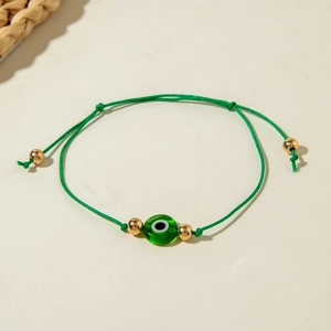 Detail of green woven Evil Eye bracelet with golden beads and adjustable bohemian cord