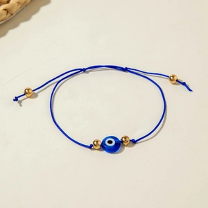 Close-up of blue woven Evil Eye bracelet with gold beads and adjustable cord