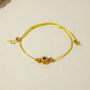 Detailed view of yellow braided evil eye bracelet with adjustable cord and gold beads