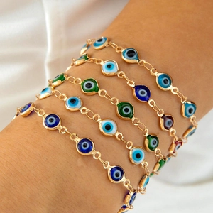 Close-up of stacked gold-plated Evil Eye charm bracelets with colorful resin beads