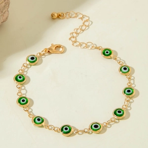 Detail view of gold beaded evil eye bracelet with green charms and lobster clasp
