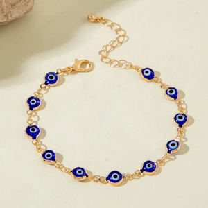 Detail of bohemian evil eye beaded bracelet with blue enamel eyes and golden chain link