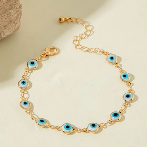 Detail showing gold chain bracelet with blue evil eye charms and a secure lobster clasp