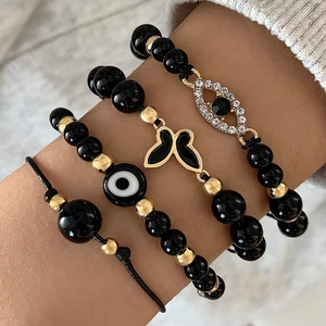 Detail of bohemian evil eye bracelets set featuring black beads and gold butterfly charms
