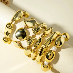 Detailed set of gold geometric bracelets with organic pebbles and pearls on display