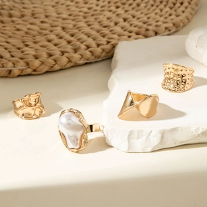Set of four gold vintage rings featuring irregular pearls and textured geometric designs