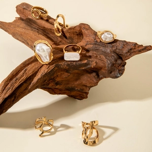 Golden baroque pearl ring set with geometric irregular designs on driftwood