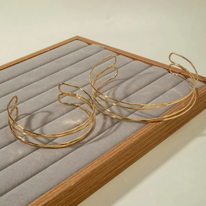 Detail of two gold open chokers with multi-layer parallel rings on gray velvet tray
