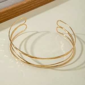 Detailed view of multilayer gold metal choker with handcrafted hammered texture and open style