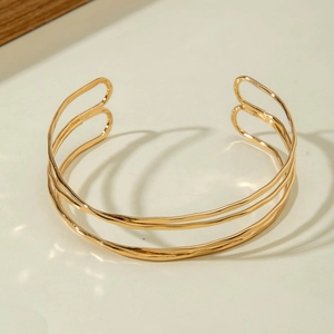Detailed view of luxury gold open cuff bracelet with triple-layered hollow wave design