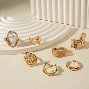 Detailed set of seven gold baroque pearl and ocean-themed rings on a white background
