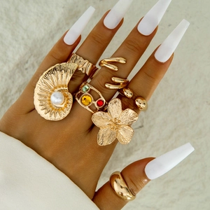 Detailed view of bohemian gold flower rings set with baroque pearls and colorful gems