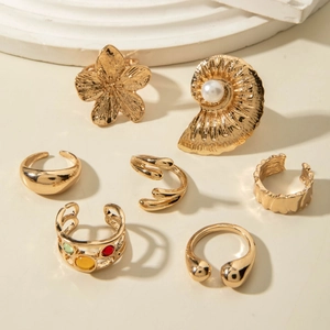 Detailed set of 7 gold rings featuring baroque pearl, flower design and mixed gemstones