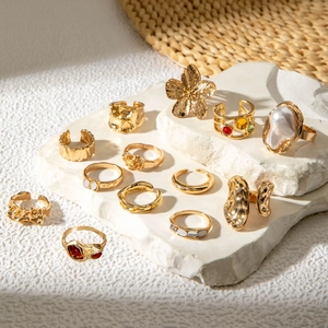 Detailed close-up of gold baroque pearl rings and floral jewelry on a stone background