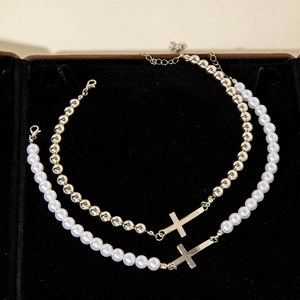 Close-up of pearl and silver bead cross necklace displayed in a black velvet jewelry box