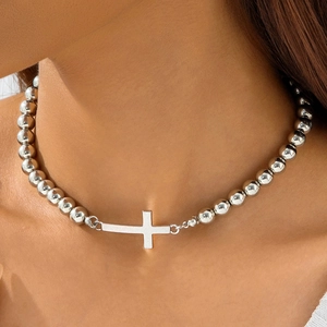 Close-up of a silver beaded necklace with horizontal cross pendant on female collarbone