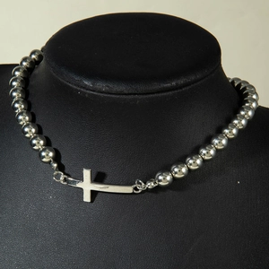 Detailed view of silver beaded necklace featuring a horizontal cross on a black neck bust