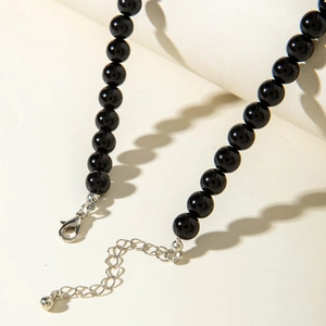 Close-up of glossy black beaded necklace with silver lobster clasp and extension chain