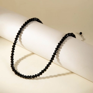 Close-up of black faceted bead choker with adjustable silver lobster clasp on white stand