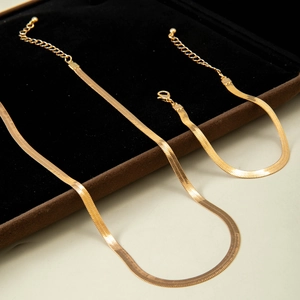 Golden flat snake chain necklace and bracelet set with polished finish on black velvet