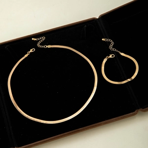 Detailed view of gold snake chain necklace and bracelet set in a black velvet jewelry box