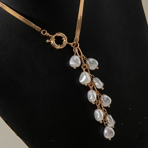 Detail of gold snake chain necklace featuring baroque pearl tassel pendant and spring clasp