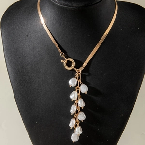 Golden snake bone chain necklace featuring a round clasp and baroque pearl pendant tassels