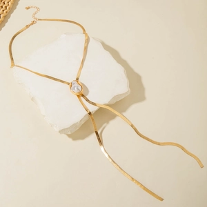 Detail of baroque pearl pendant on a gold snake chain necklace over stone textures