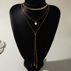Détail du collier à plusieurs rangs doré avec pendentif cœur et chaîne longue en Y