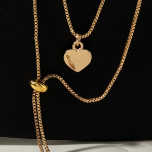 Détail du pendentif cœur doré sur chaîne à mailles carrées avec perle réglable