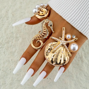 Detailed view of ocean-themed gold ring set with seahorse, shell and pearl accents