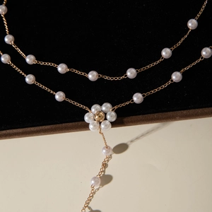 Collier double rang doré avec pendentifs fleurs en perles sur fond de velours noir