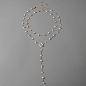 Vue détaillée du collier doré multicouche avec fleur en perles et long pendentif