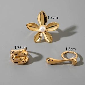 Three-piece gold metal ring set featuring floral pearl design and wavy textured bands