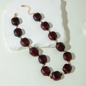 Macro detail of dark brown acrylic chunky chain necklace with golden lobster clasp