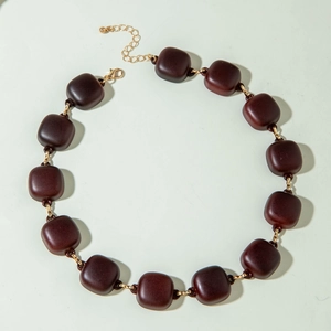 Close-up of matte dark brown acrylic rectangular beads on a golden chain necklace