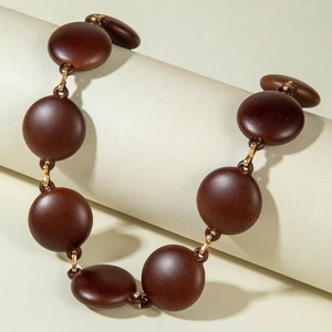 Detail of chunky acrylic necklace with matte brown discs and gold metal links