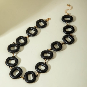 Detailed view of black matte square links and gold metal connectors on this modern necklace