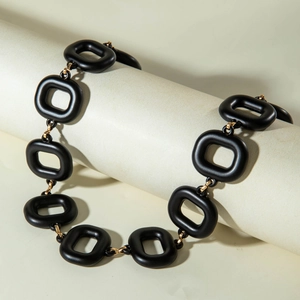 Detail view of matte black square links and gold metal rings on a minimalist necklace