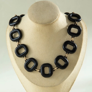 Close-up of black matte acrylic rectangular links with golden metal chain segments