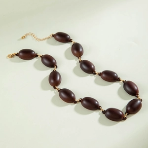 Close-up of brown oval acrylic beads on a gold metal chain necklace with lobster clasp