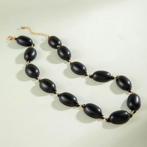 Detailed view of matte black oval beads with gold metal links and adjustable clasp