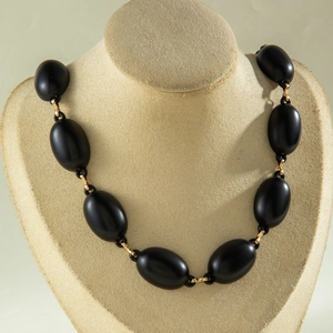 Close-up of matte black acrylic beads with gold metal ring links on mannequin neck