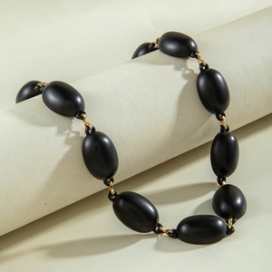 Macro detail of matte black oval beads and gold metal links on a stylish necklace