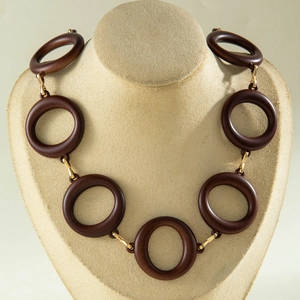 Detail of chunky dark brown wooden ring necklace with golden metal connectors on a bust