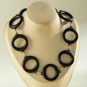 Detailed view of matte black acrylic rings with gold metal links on a display bust