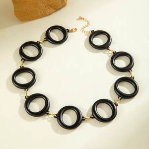 Close-up of matte black acrylic rings linked by gold-tone hardware for minimalist necklace