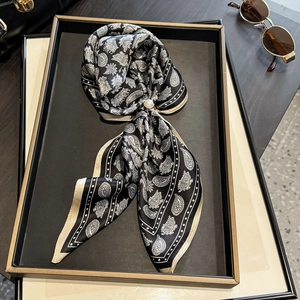 Eleganter schwarz-weißer Paisley-Seidenschal mit Perlenschnalle auf einem Tablett